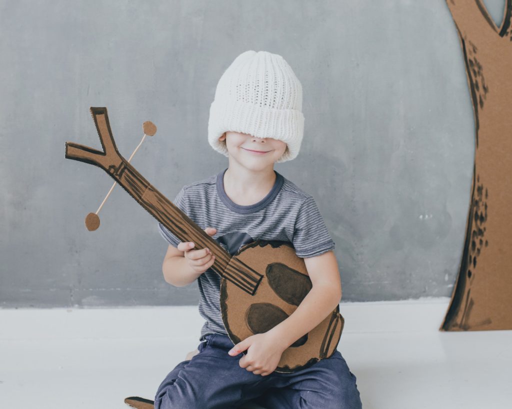 Psihološka podpora - vesel otrok, ki se igra s kitaro iz kartona